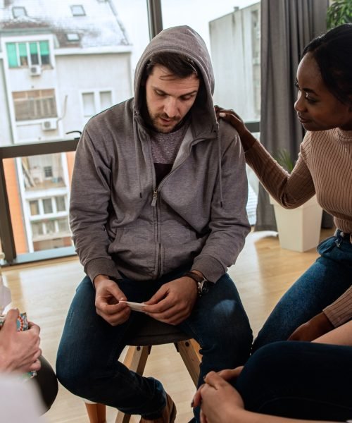 Diverse group of people sitting in circle in group therapy session.